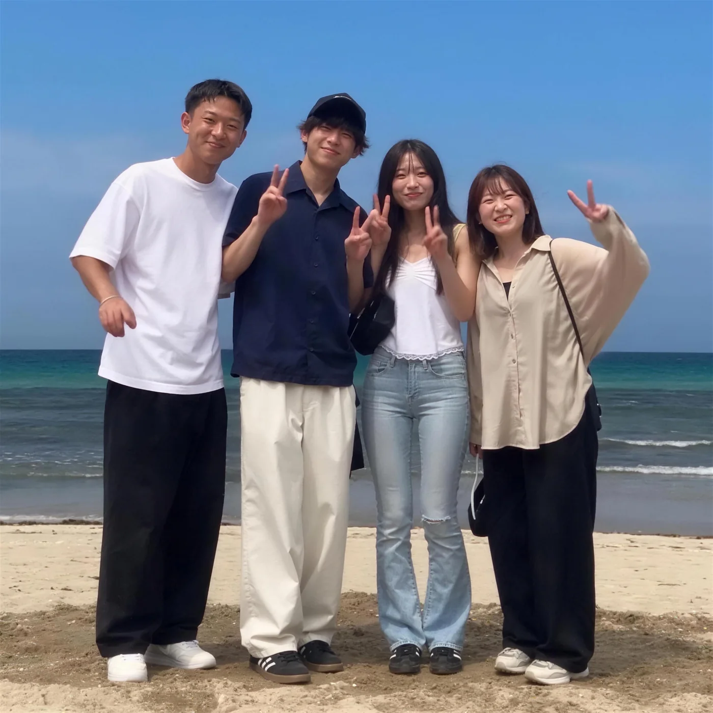 砂浜で記念写真を撮る男女4人